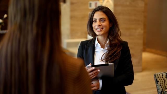 Hotelrezeption mit Mitarbeiterin im Gespräch mit einem Gast